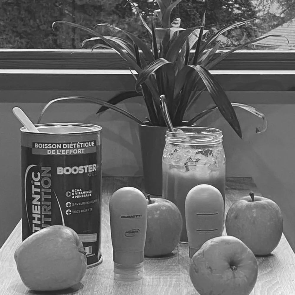 Boîte de boisson énergétique Booster Authentic Nutrition entourée de pommes fraîches pour une recette sportive.