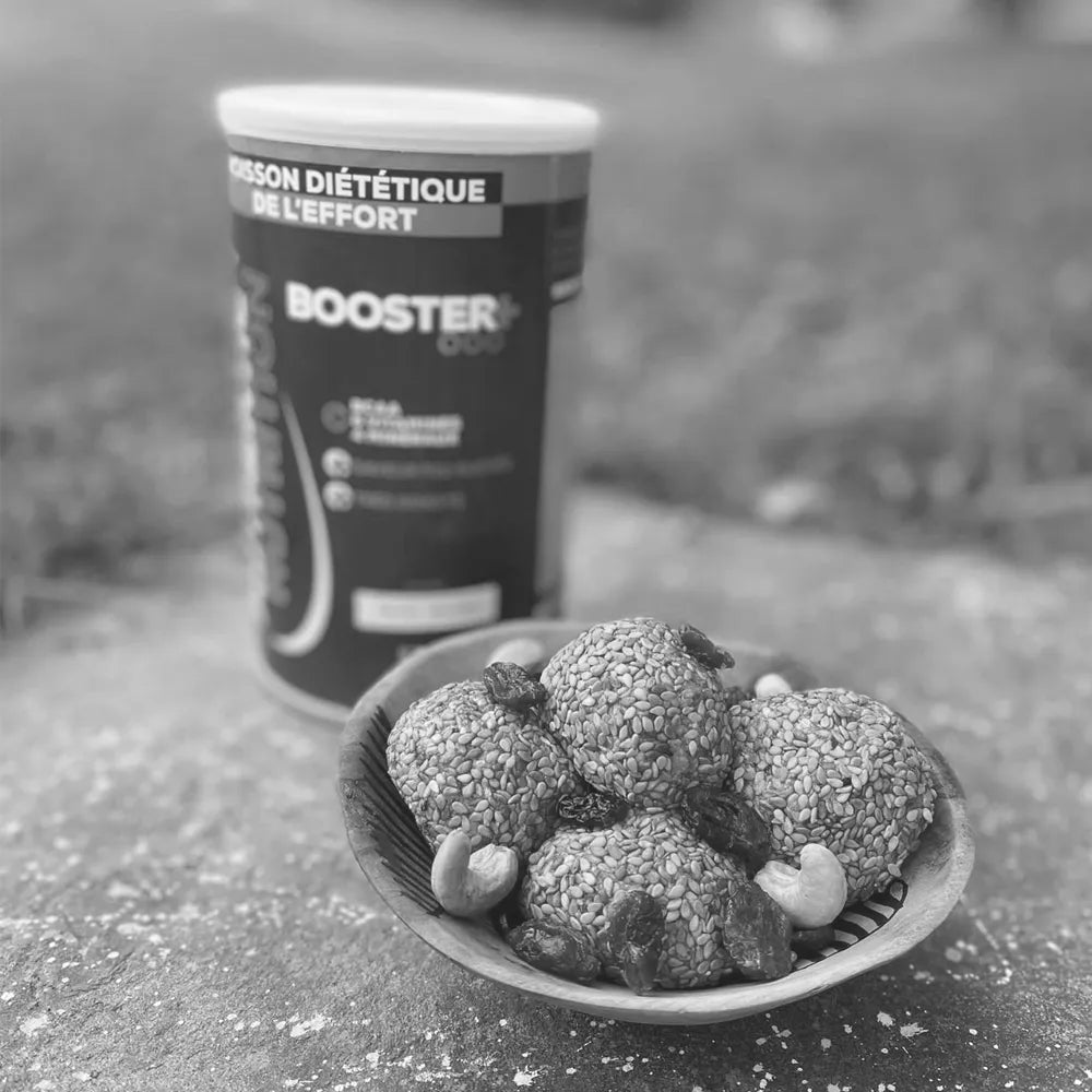 Boules énergétiques maison aux sésames et cajou à côté d'une boîte de Booster+ Authentic Nutrition.