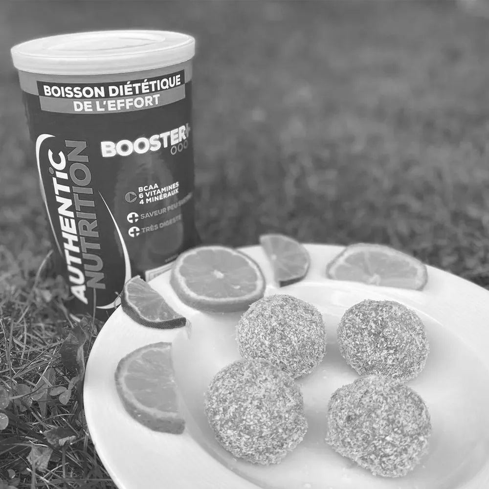 Energy balls à la noix de coco et citrons à côté d'une boîte de boisson Booster+ Authentic Nutrition.