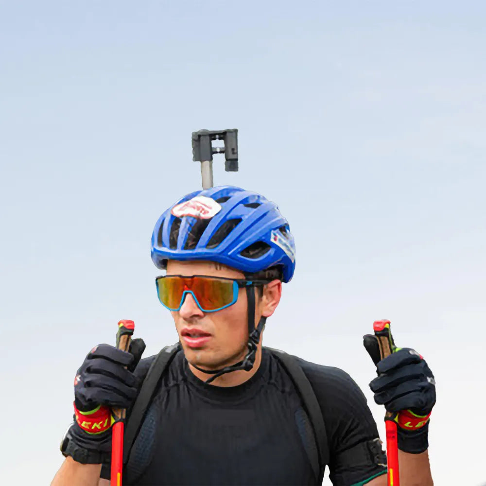 Portrait de face du biathlète Oscar Lombardot équipé de son bonnet, lunettes de soleil et carabine de tir.